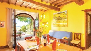 Un comedor con una mesa dispuesta para dos, un banco y vistas a un patio exterior por un arco abierto.