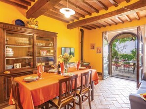 Zona pranzo con tavolo apparecchiato per quattro persone, mobili contenitori in legno e vista su un patio esterno da una porta aperta.