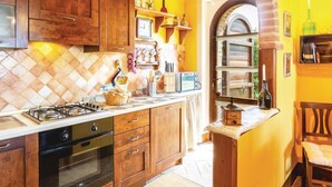 Una cocina con armarios de madera, estufa a gas y salpicadero de azulejos.