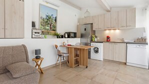 A modern kitchen with a dining area, a washing machine, and a sofa. - Studio Apartment 'Les Cyclamens - Les Oliviers' with Shared Pool, Wi-Fi and Air Conditioning (Saint-Raphaël)