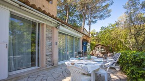 A patio with a table and chairs, a sliding glass door, and a stone floor. - Studio Apartment 'Les Cyclamens - Les Oliviers' with Shared Pool, Wi-Fi and Air Conditioning (Saint-Raphaël)