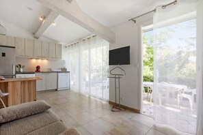 Une cuisine moderne avec des meubles en bois, un coin repas avec une table et des chaises, et un balcon offrant une vue sur la verdure.