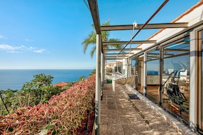 A balcony with a view of the sea, a glass door, and a treadmill.