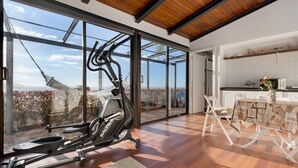 A spacious room with a large window, a ceiling fan, and a dining area with a table and chairs.