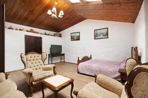 Une pièce avec un plafond en bois, un lit, une télévision et une chaise.