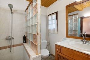 Une salle de bain équipée d’une douche, de toilettes, d’un lavabo et d’un miroir.