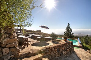 A stone patio with outdoor furniture, a pool, and a view of the landscape.