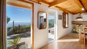 A room with a wooden ceiling, a view of the outdoors, a door leading outside, and a kitchen area with cabinets. - Vacation Home "El Cazador 2" with Sea View, Shared Pool & Wi-Fi (granadilla)