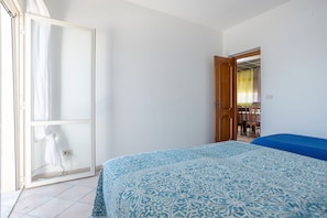 A bedroom with a bed, a wardrobe, and an open door leading to a balcony.