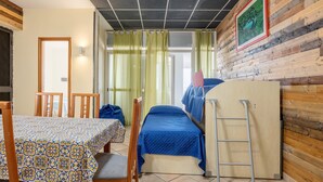 Een kamer met een bed, een tafel met stoelen, een ladder en een houten wand met een lijstwerk.