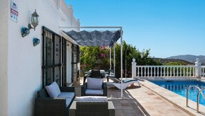 Un patio con muebles de mimbre, una piscina y vistas a las colinas.