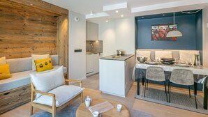 Una sala de estar moderna con una pared de acento de madera, un sofá con cojines amarillos, una silla de madera y una mesa de centro redonda.