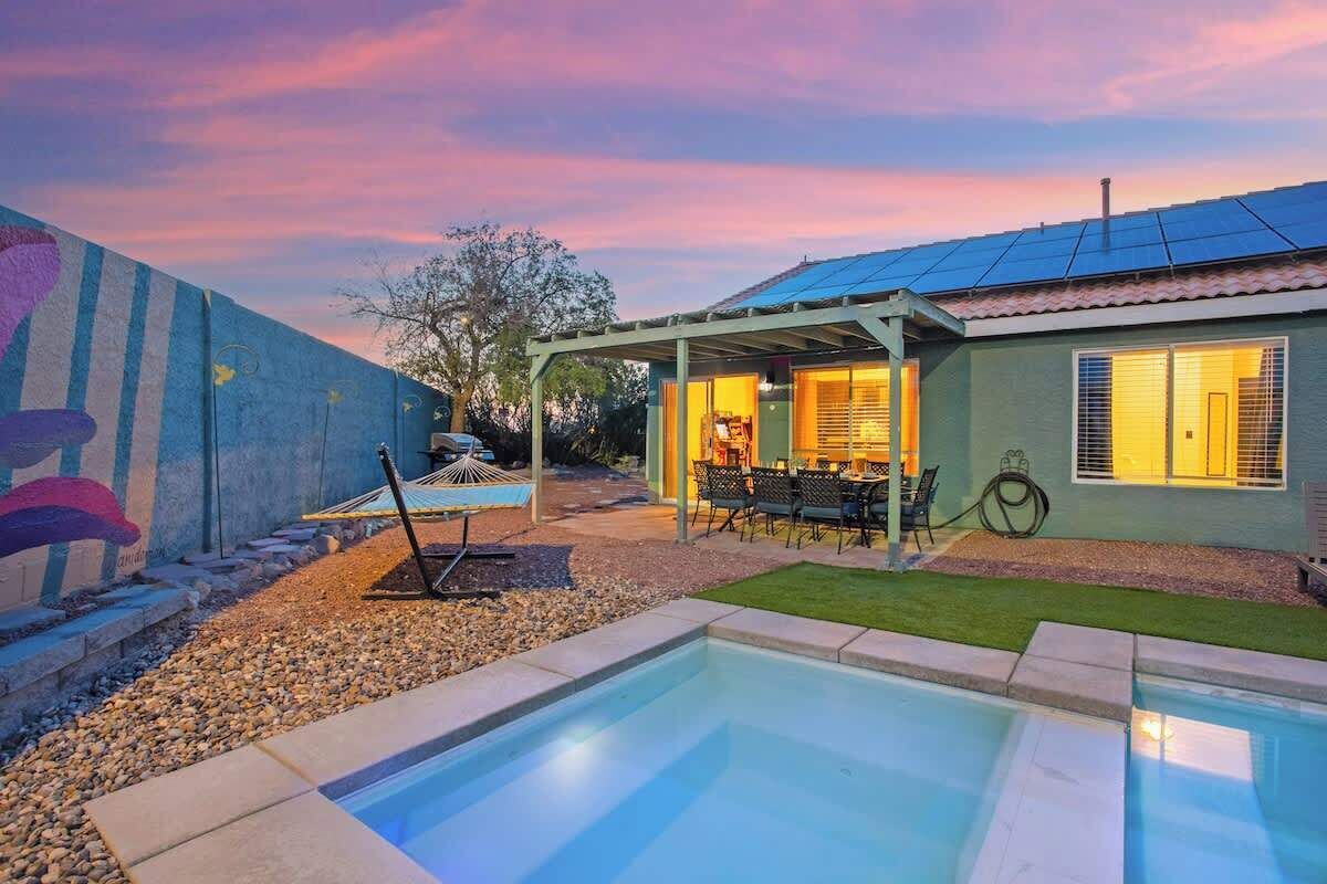 A residential property with a swimming pool, outdoor seating area, and a covered patio.