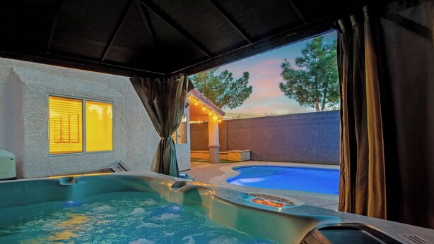 A hot tub with a view of a backyard and a sunset. - Vegas 5BR: Movie Theater, Pool, Hot Tub & Arcade (North Las Vegas)