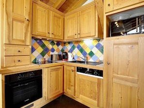 A kitchen with wooden cabinets, a Bosch oven, a coffee maker, and a microwave. - Charming duplex with fireplace and wifi in Courchevel (Courchevel 1550)