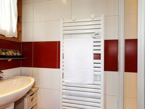 A bathroom with a white sink, a towel rack, and a shower with a white towel. - Charming duplex with fireplace and wifi in Courchevel (Courchevel 1550)