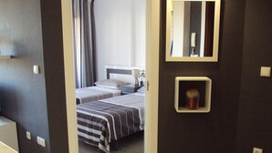 A hotel room with two beds, a bedside table, a mirror, and a small shelf with a cactus. - Stunning 1 bedroom apartment with clear views across Benidorm (Benidorm)
