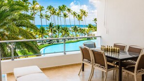 A balcony with a pool view, a dining table with chairs, and a white sofa.