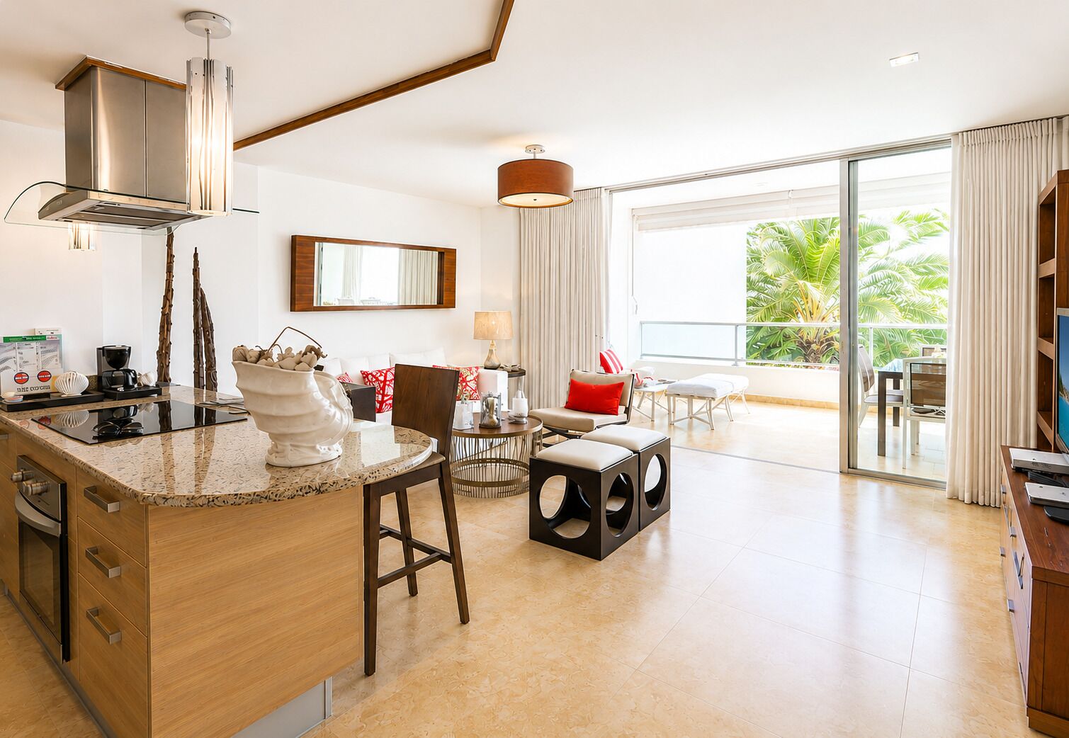 Una cocina moderna con una isla central, un comedor con mesa redonda y un balcón con vistas a zonas verdes.