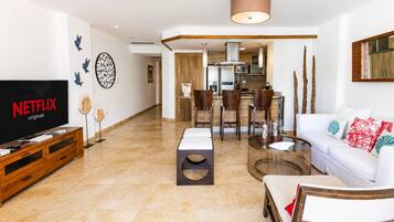 Una sala de estar moderna con televisor de pantalla plana, comedor y cocina.