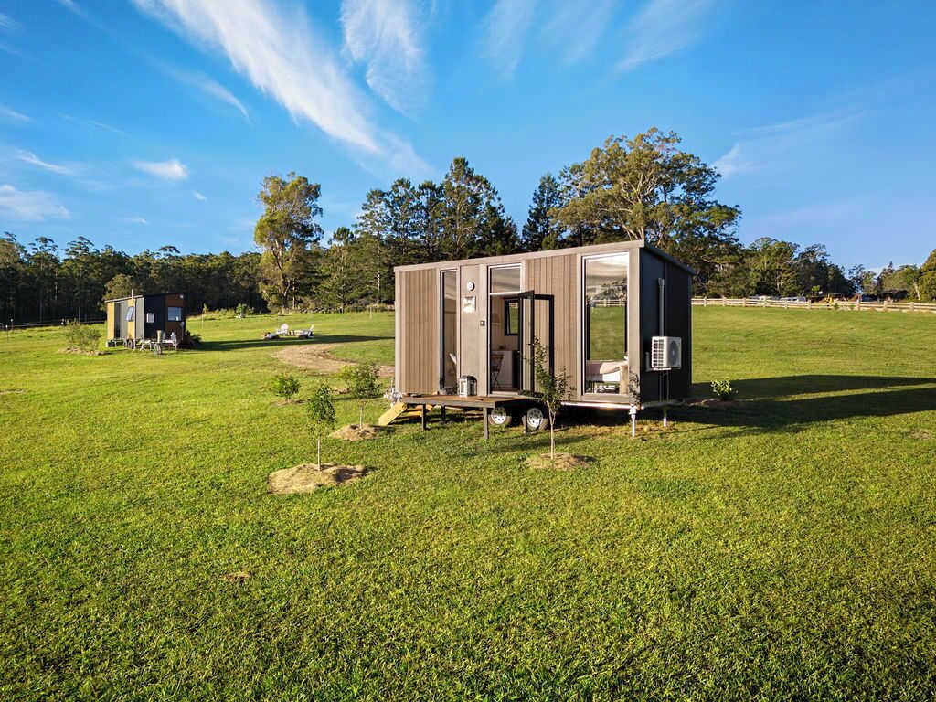 A small, single-story mobile home with a sliding door, a small porch, and a compact kitchen area.