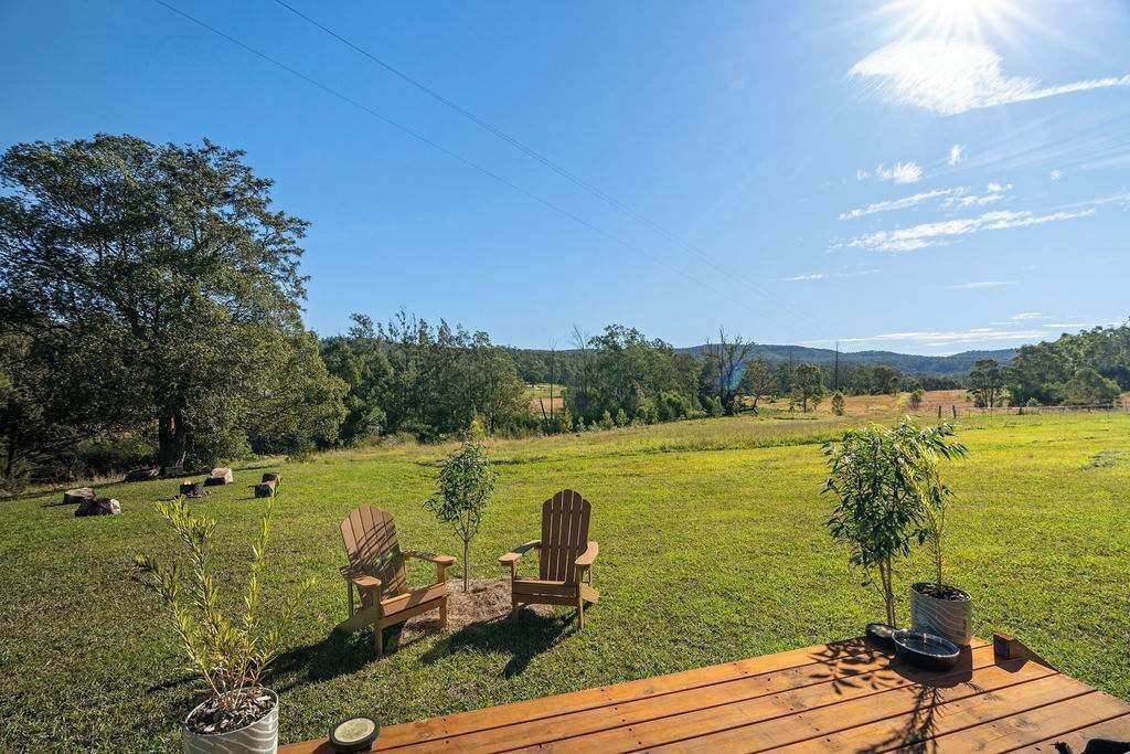 An outdoor seating area with Adirondack chairs, a wooden table, and potted plants.