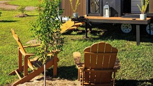 A modern mobile home with a deck, outdoor seating, and a small garden area. - Tiny Tallowood by Tiny Away (Glenreagh)