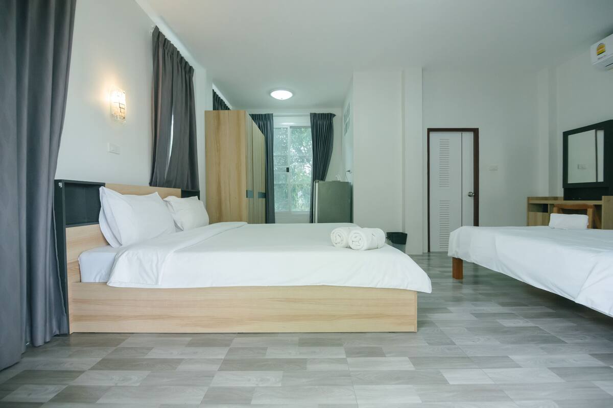 A hotel room with a large bed, a smaller bed, a desk, and a wardrobe.