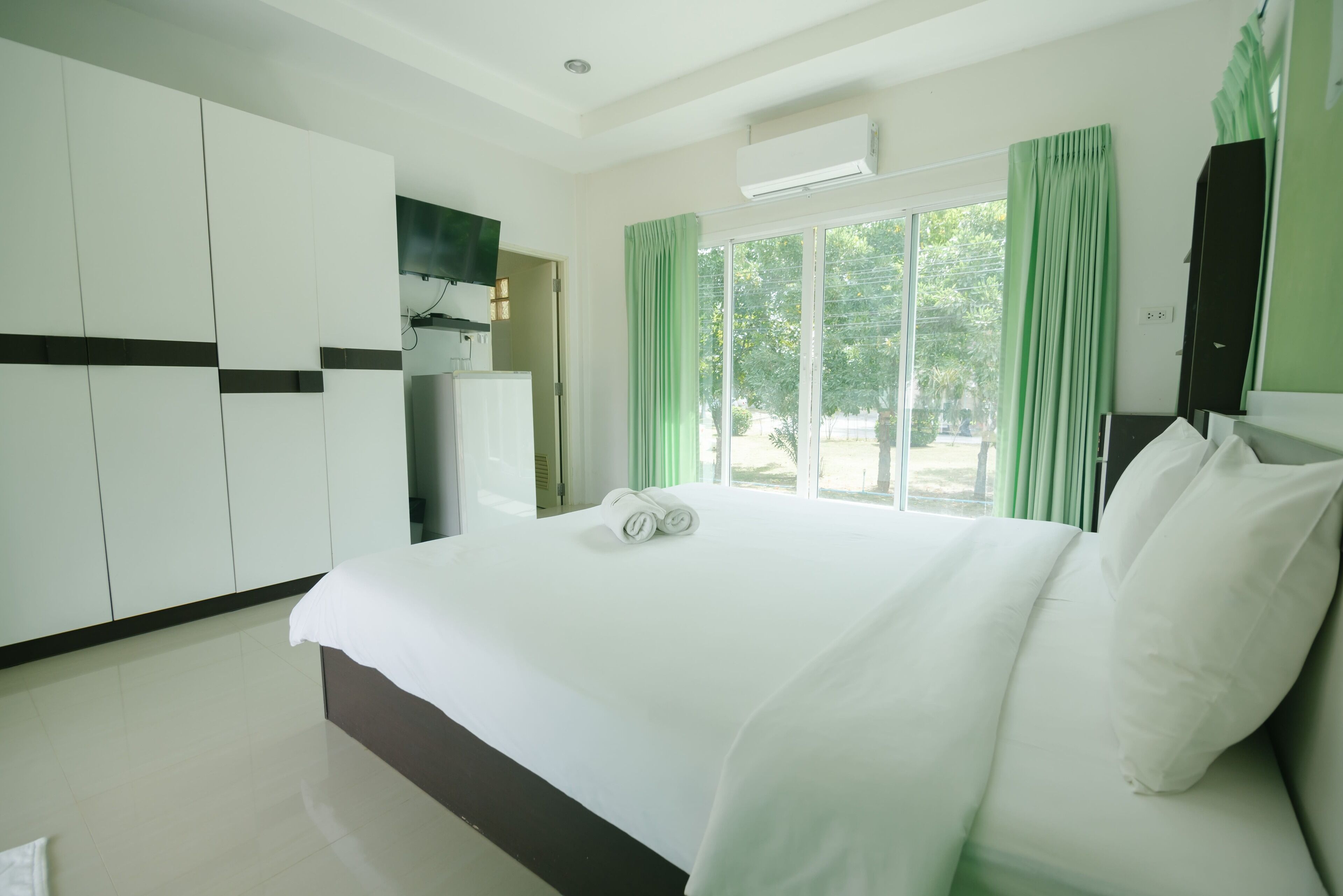 A hotel room with a large bed, a wardrobe, and a window with curtains.