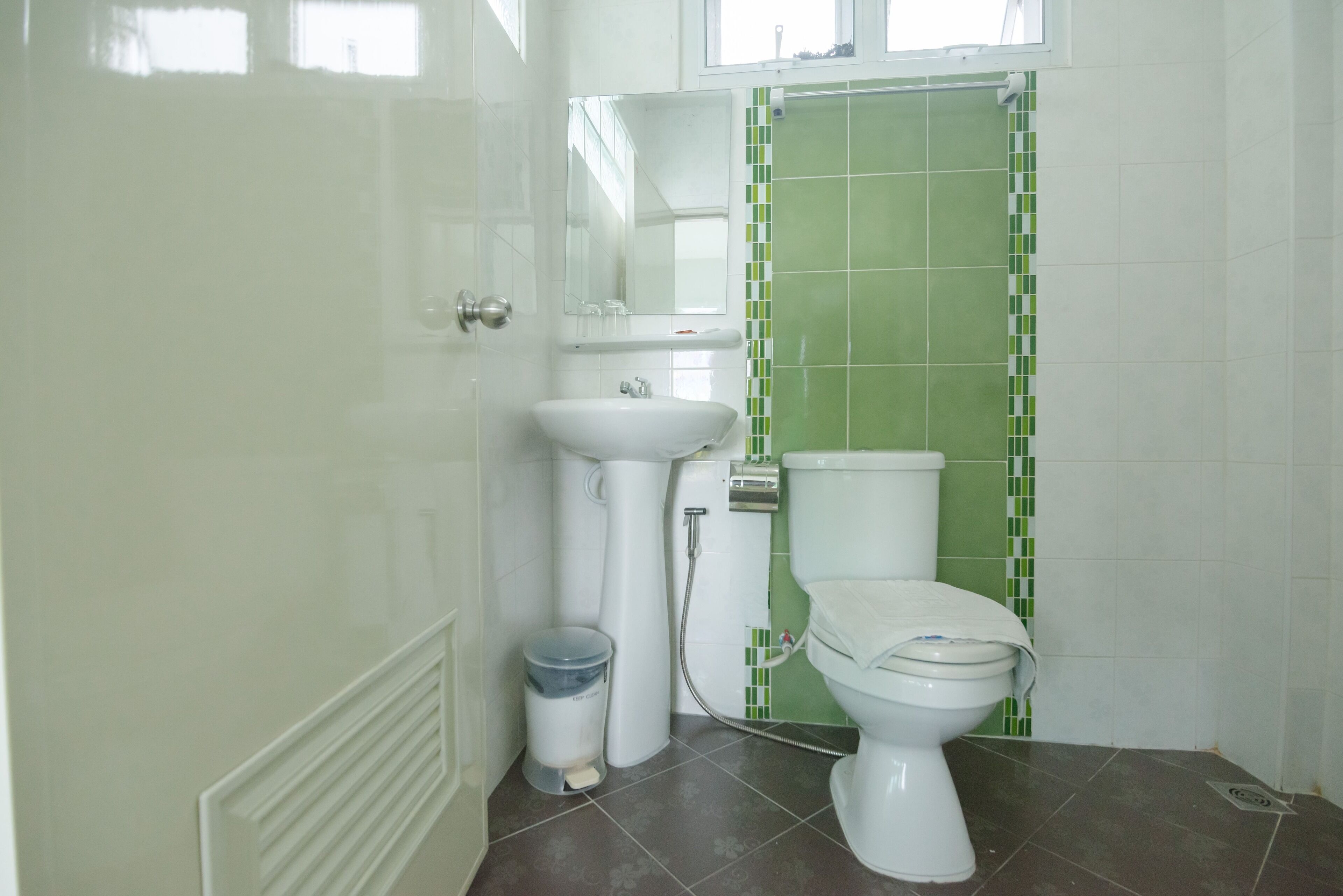 A bathroom with a toilet, sink, and mirror.
