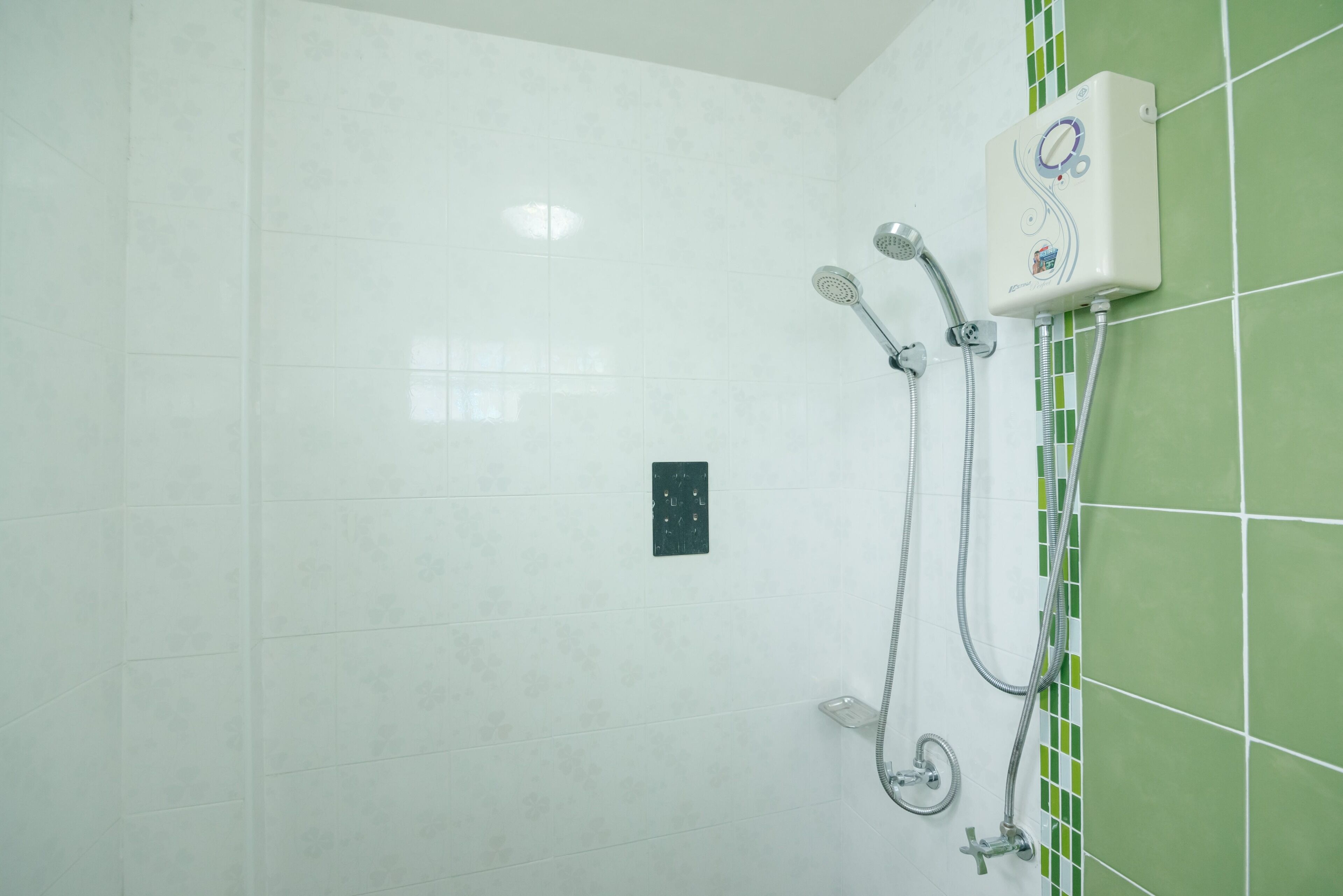 Casa de banho com chuveiro, painel de controlo e paredes com azulejos verdes.