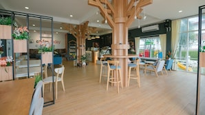 A modern interior with wooden furniture, a bar area, and large windows. - Reuan Chom Dao Resort (Chom Bueng)