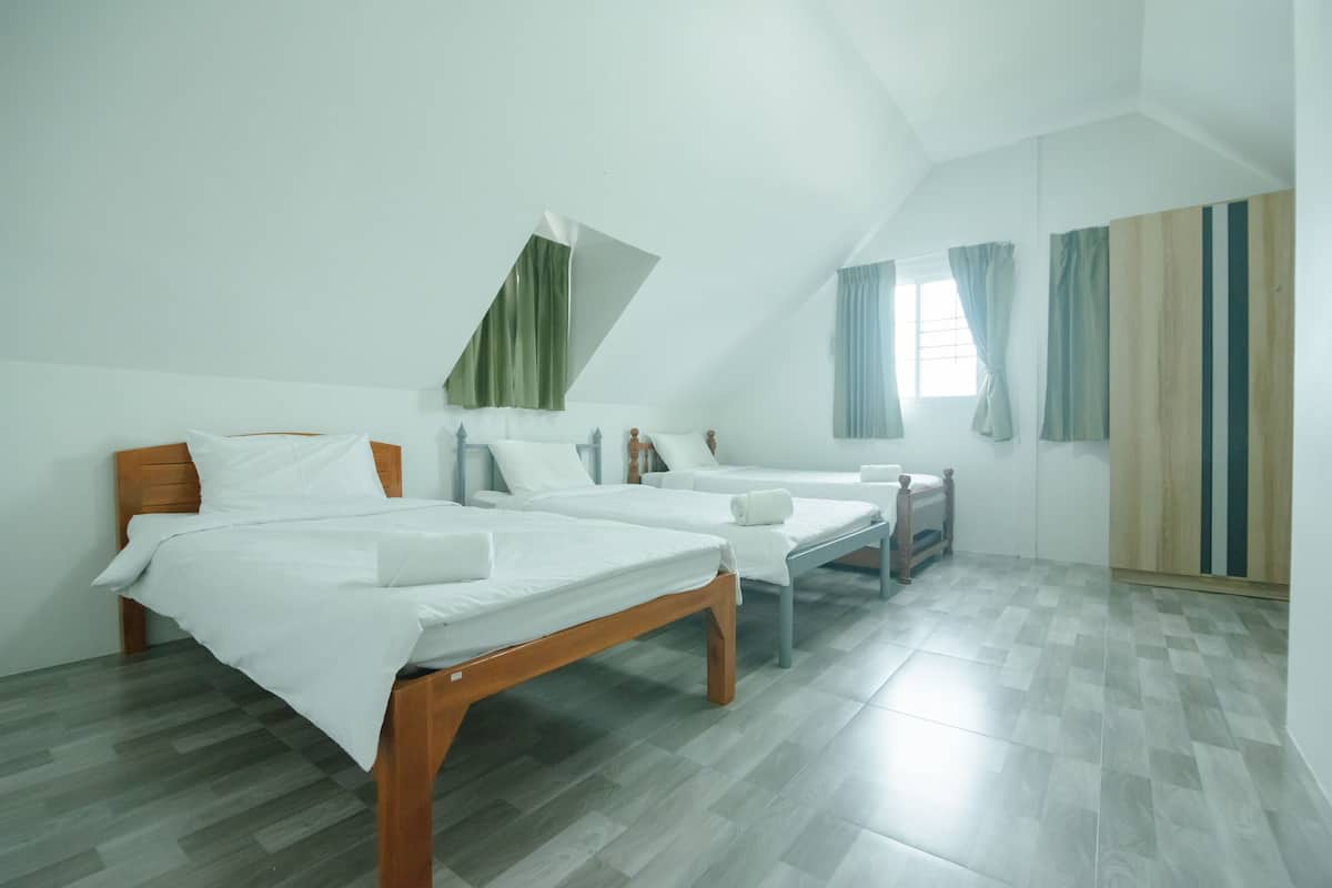 A room with two beds, a small table, and a window with curtains.