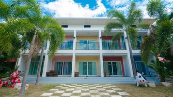 A two-story building with a checkered lawn in front, palm trees, and a colorful sculpture.