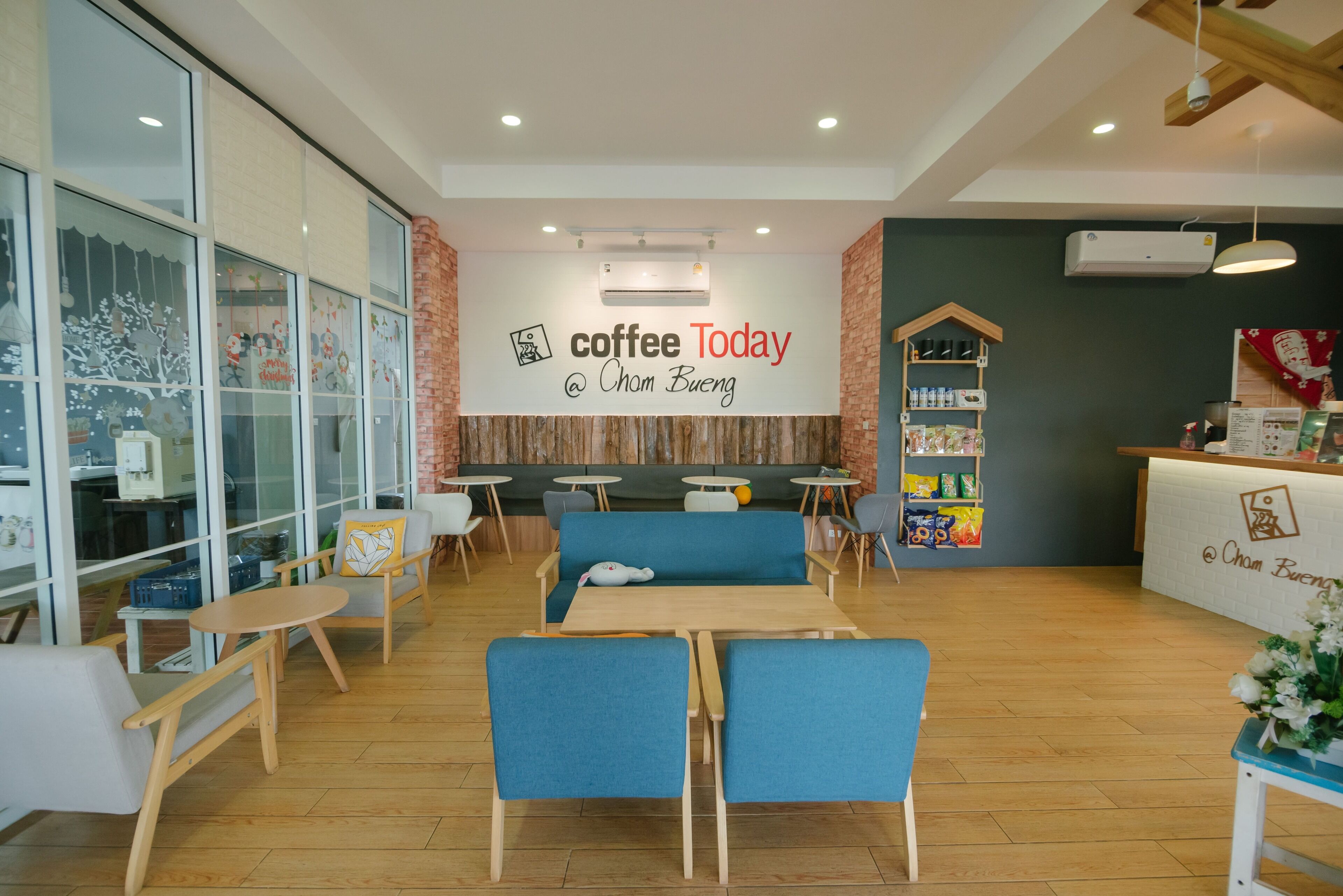 A modern coffee shop interior with seating, a counter, and a wall with the text "coffee Today @ Cham Bueng".