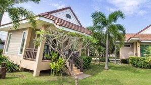 Two single-story houses with sloped roofs, surrounded by lush greenery and palm trees. - Reuan Chom Dao Resort (Chom Bueng)