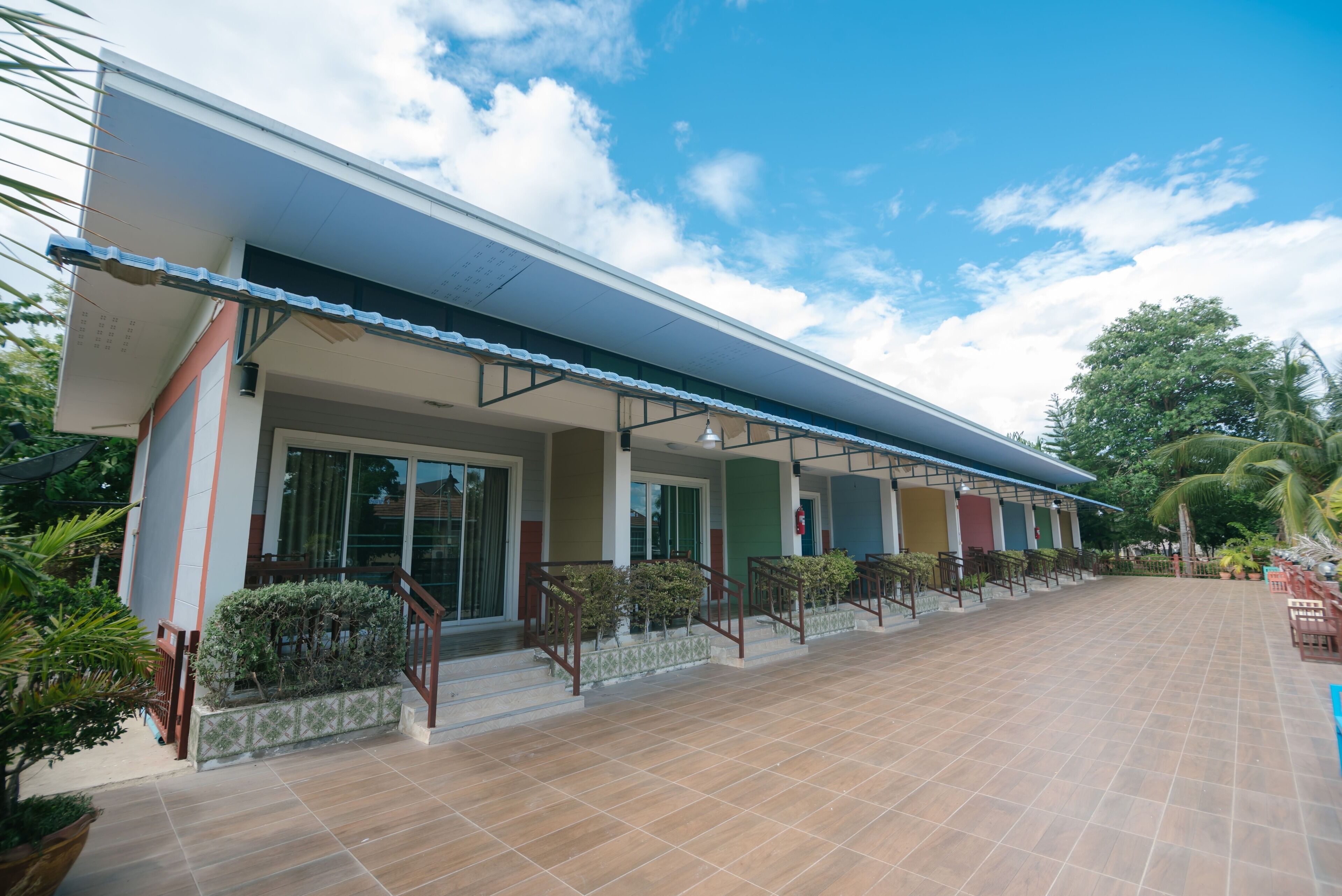Un hotel con galería techada, varias habitaciones y un patio con baldosas.