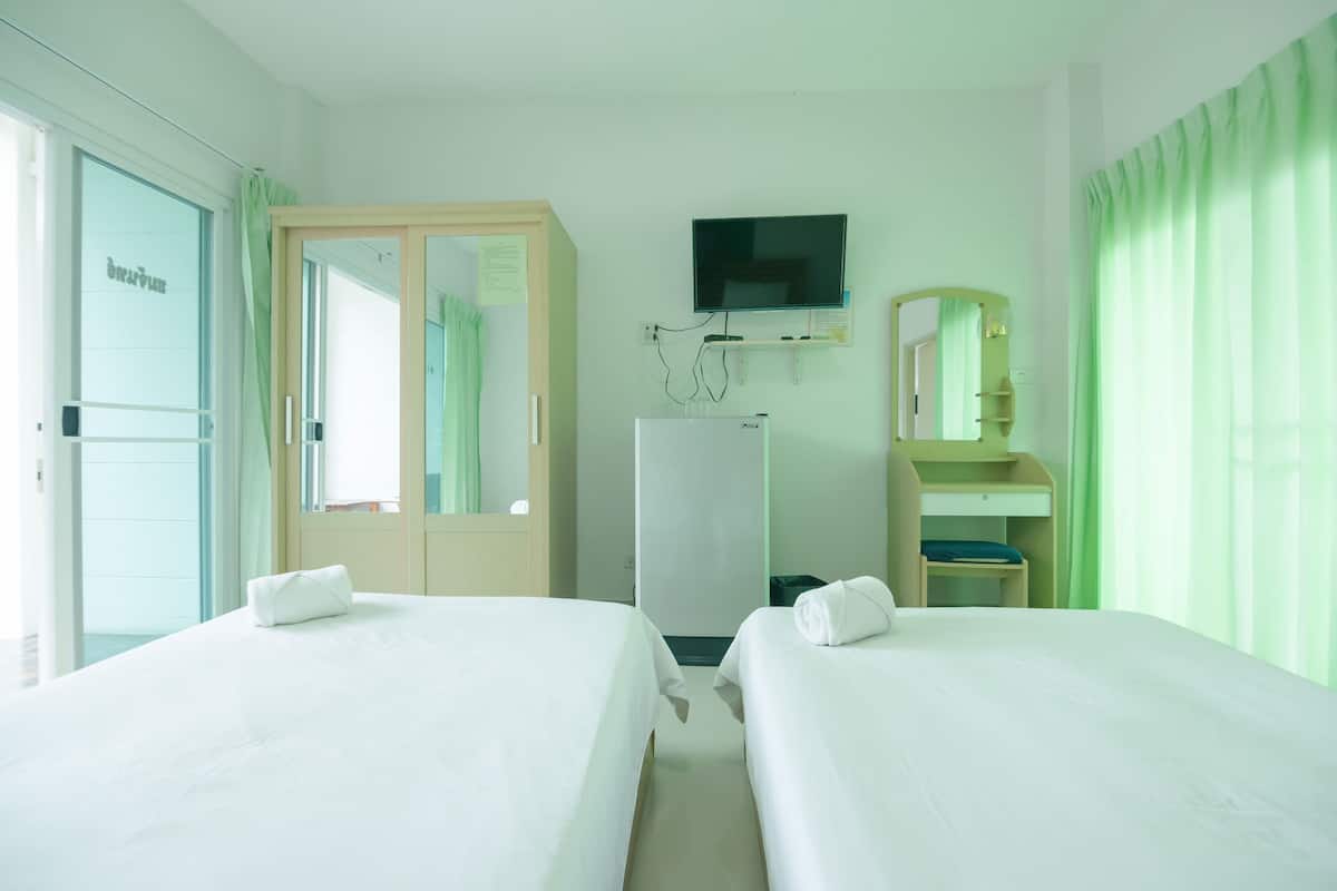 A hotel room with two beds, a TV, a mirror, and a wardrobe.