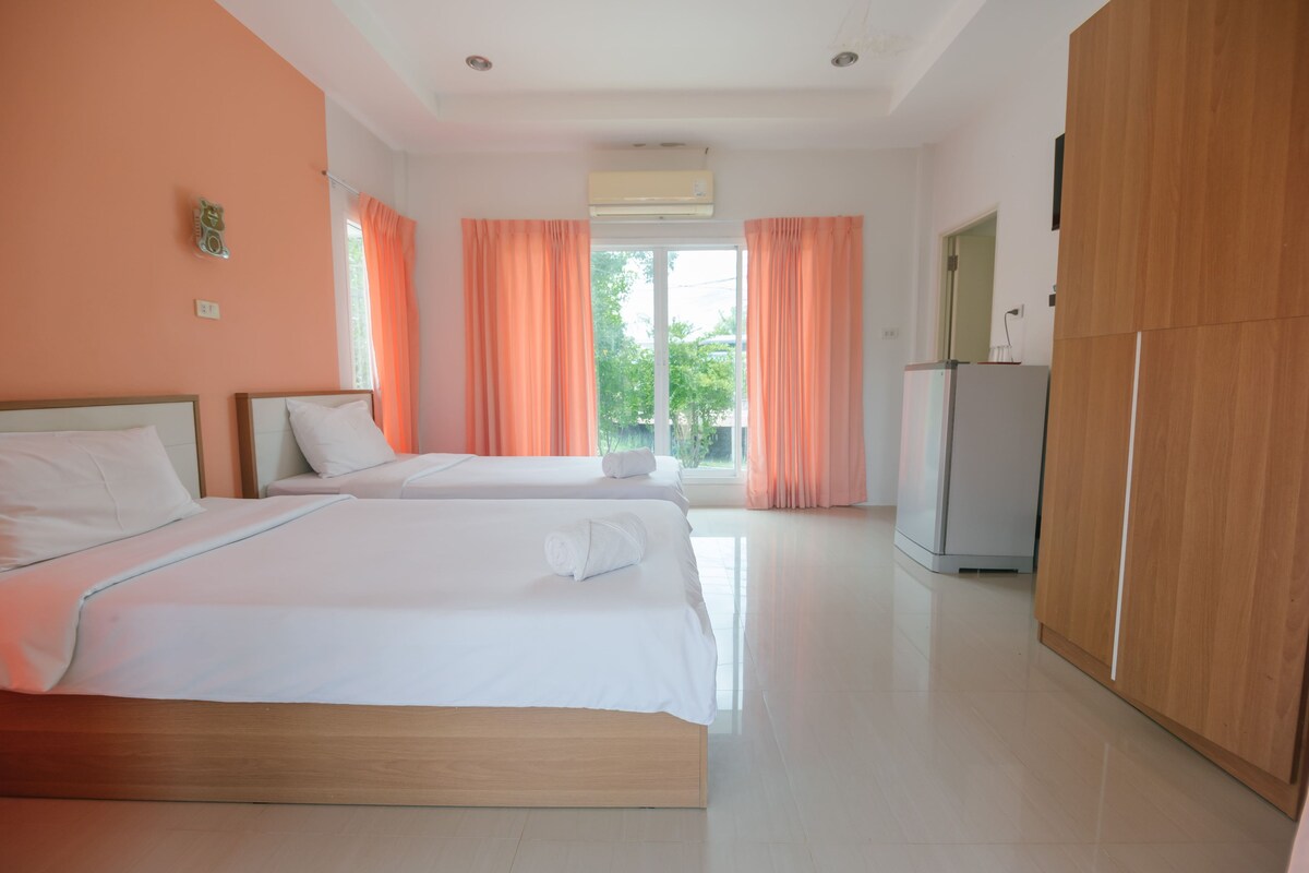 Une chambre d’hôtel avec deux lits, une armoire, la climatisation et une vue sur la verdure.