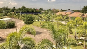 A residential area with houses, a blue building, and a paved road. - Reuan Chom Dao Resort (Chom Bueng)