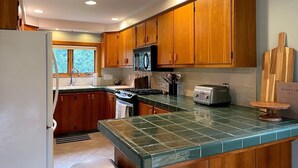 Una cocina con armarios de madera, estufa, microondas y tostadora.