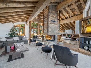 Cozy living area with fireplace, sofas, and bookshelf, offering views of the surrounding landscape.