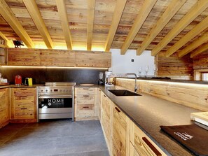A modern kitchen with wooden cabinetry, a stainless steel stove, and a black countertop.