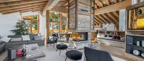 A spacious living room with a high ceiling, wooden beams, a fireplace, and a cozy seating area.