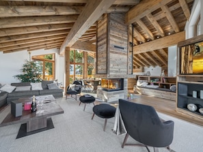 A spacious living area with a fireplace, wooden beams, and a cozy seating arrangement. - Luxury Chalet 10 pers, SPA, pool, WiFi, Courchevel 1550 (Courchevel 1550)