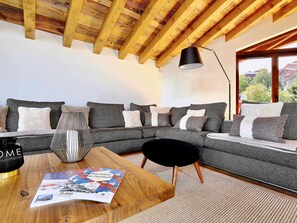 A modern living room with a sectional sofa, a wooden coffee table, and a magazine.