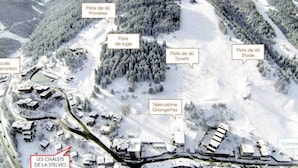 A ski resort with marked ski slopes, a cable car station, and chalets.