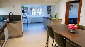 Une cuisine moderne avec un coin repas, comprenant un îlot central, un four encastré et une vue sur la salle à manger.