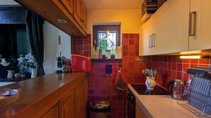 A compact kitchen with wooden cabinets, a tiled backsplash, a sink, and a window. - Cosy duplex for 6 with 2 balconies & parking in La Clusaz (La Clusaz)