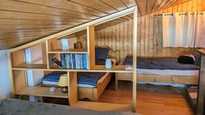 A compact room with a sloped ceiling, wooden walls, and a bunk bed. There is a small desk with a lamp and a shelf with books. - Cosy duplex for 6 with 2 balconies & parking in La Clusaz (La Clusaz)